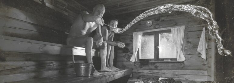 Two people relaxing in a sauna, throwing water on the heater.