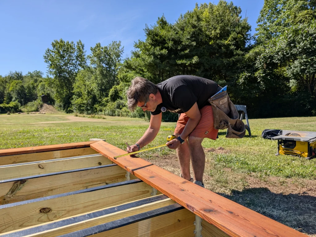 Person measuring and preparing to build Thermory Kodiak Spruce deck for sauna kit