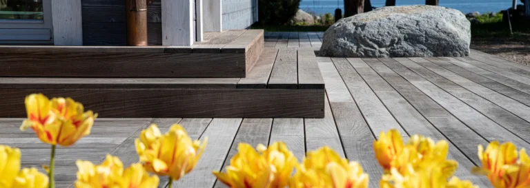 Thermory Benchmark Ash aged decking in the spring with flowers
